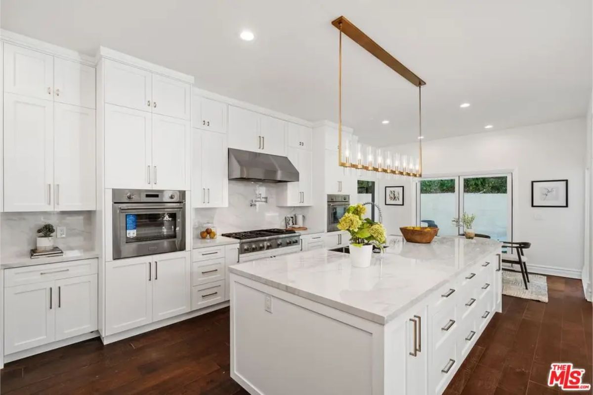 Modern gourmet kitchen featuring a large center island, high-end appliances, and white cabinetry. 