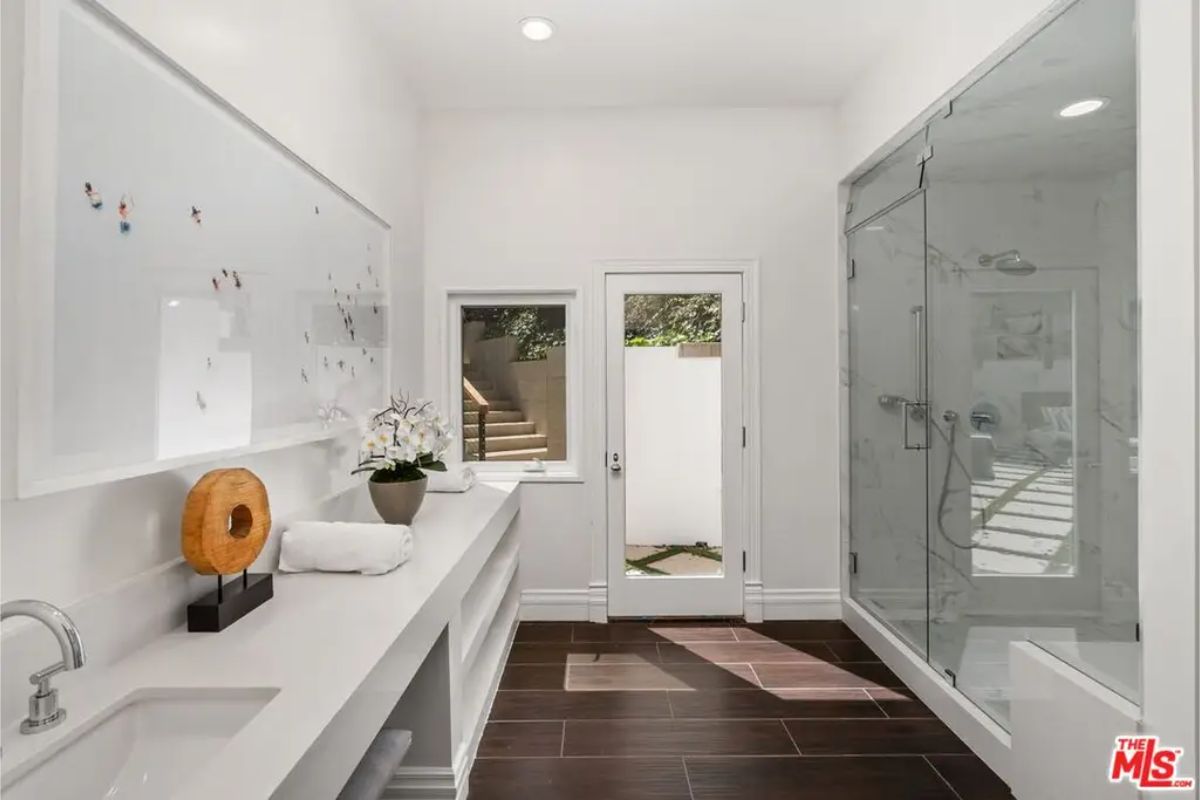 Sleek modern bathroom with a glass-enclosed shower, natural lighting, and a minimalist aesthetic. 