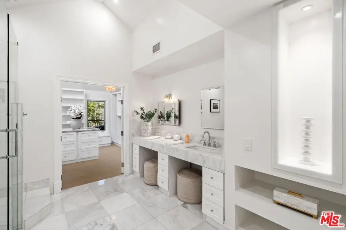 Elegant bathroom with a dual vanity, marble flooring, and built-in display shelves. 
