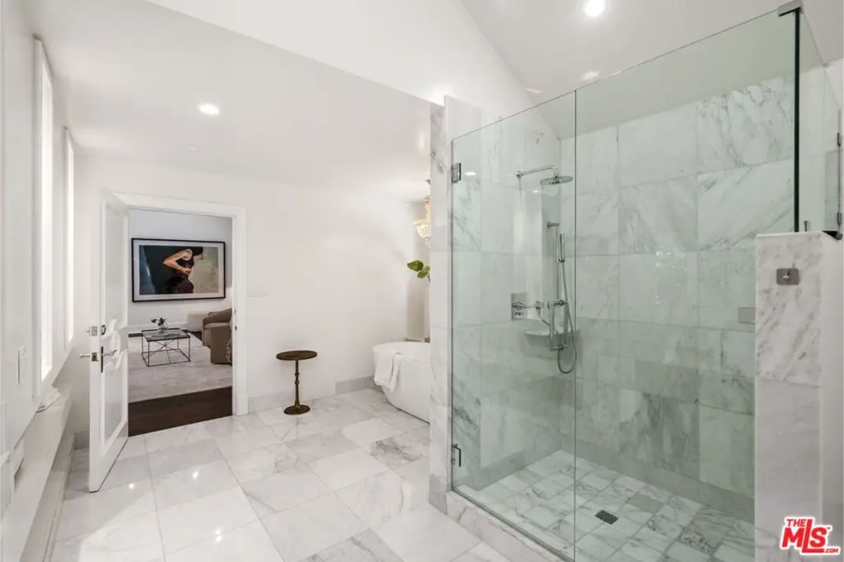 Spa-like bathroom featuring a spacious glass shower, marble flooring, and soft lighting. 
