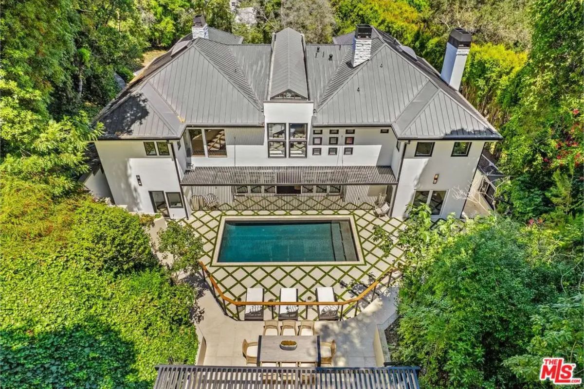 Aerial view of the grand estate, showcasing its luxurious backyard, pool, and surrounding greenery. 
