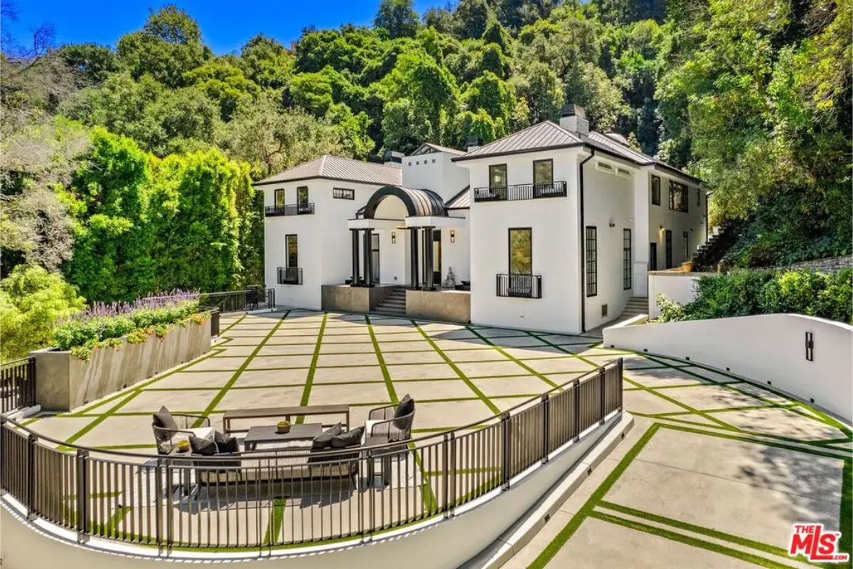 Expansive driveway and outdoor seating area with a scenic backdrop of trees and nature. 