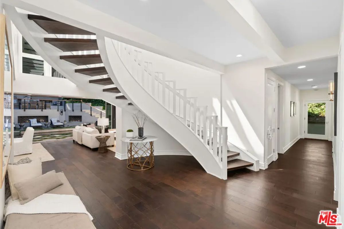 Bright foyer featuring a dramatic curved staircase, dark wood flooring, and modern decor. 