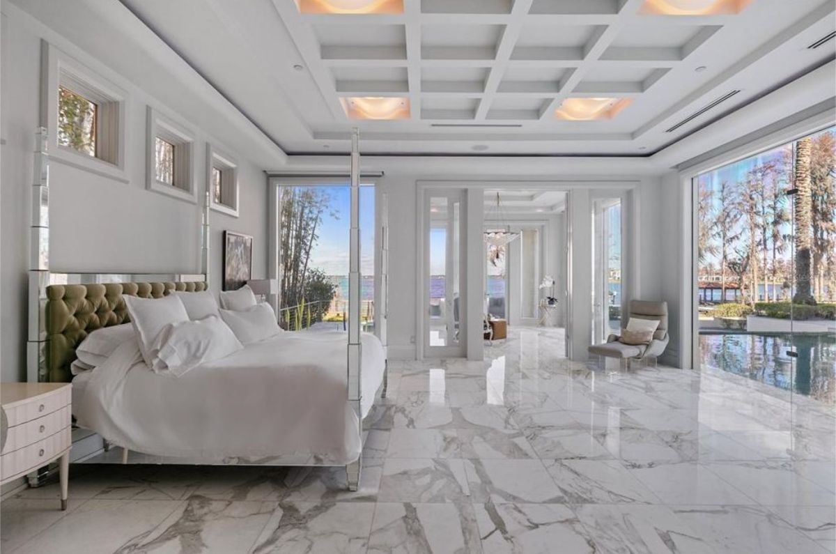 Stunning master bedroom with marble flooring, floor-to-ceiling windows, and a canopy bed. 