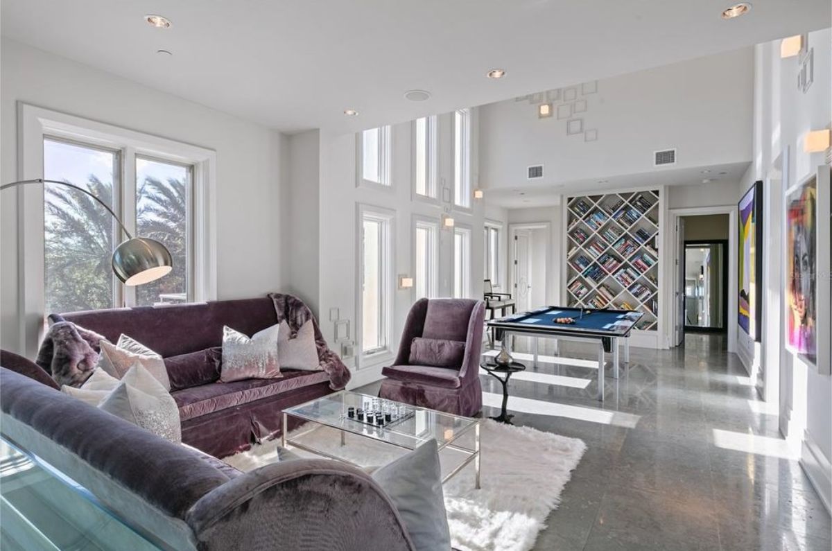 Chic entertainment room with a pool table, plush purple seating, and modern artwork. 