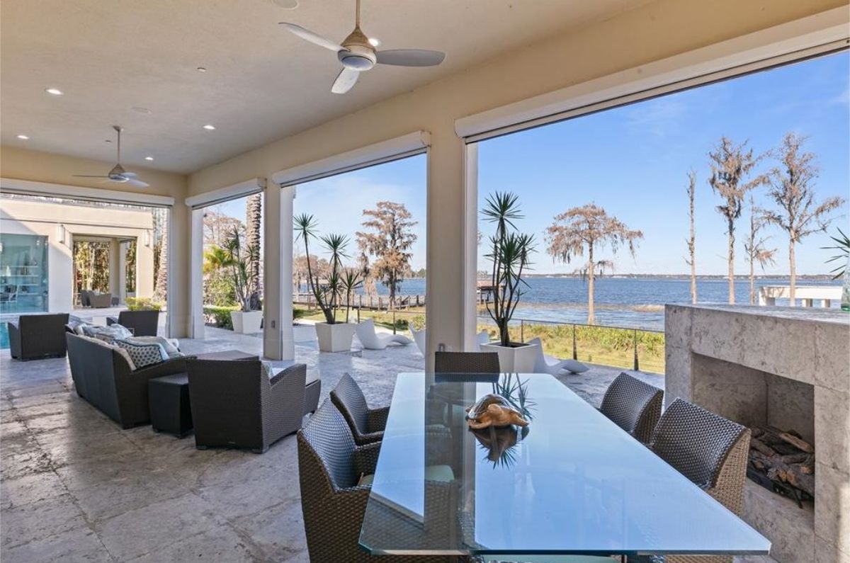 Open-air patio with a glass dining table, cozy seating, and a breathtaking waterfront view. 