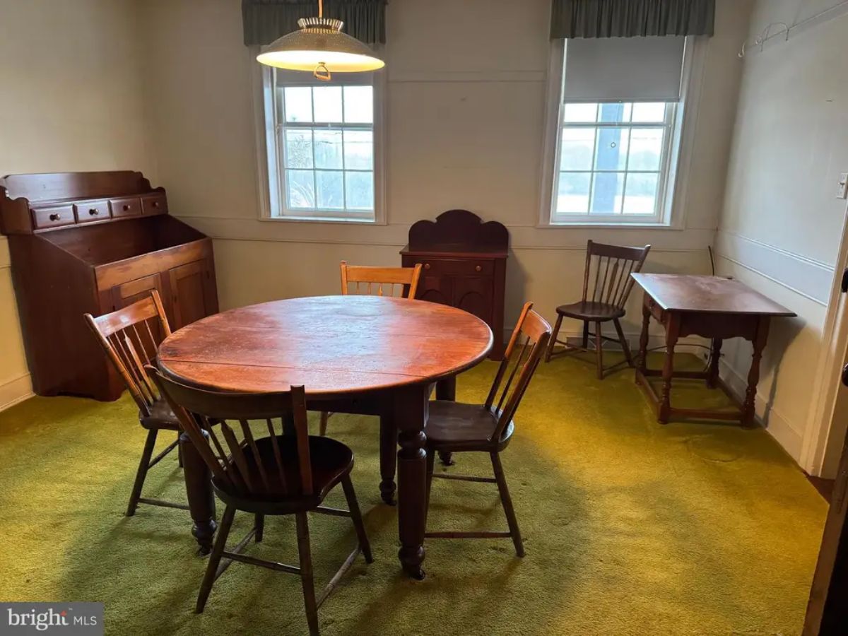 A dining room with a round wooden table and four matching chairs.