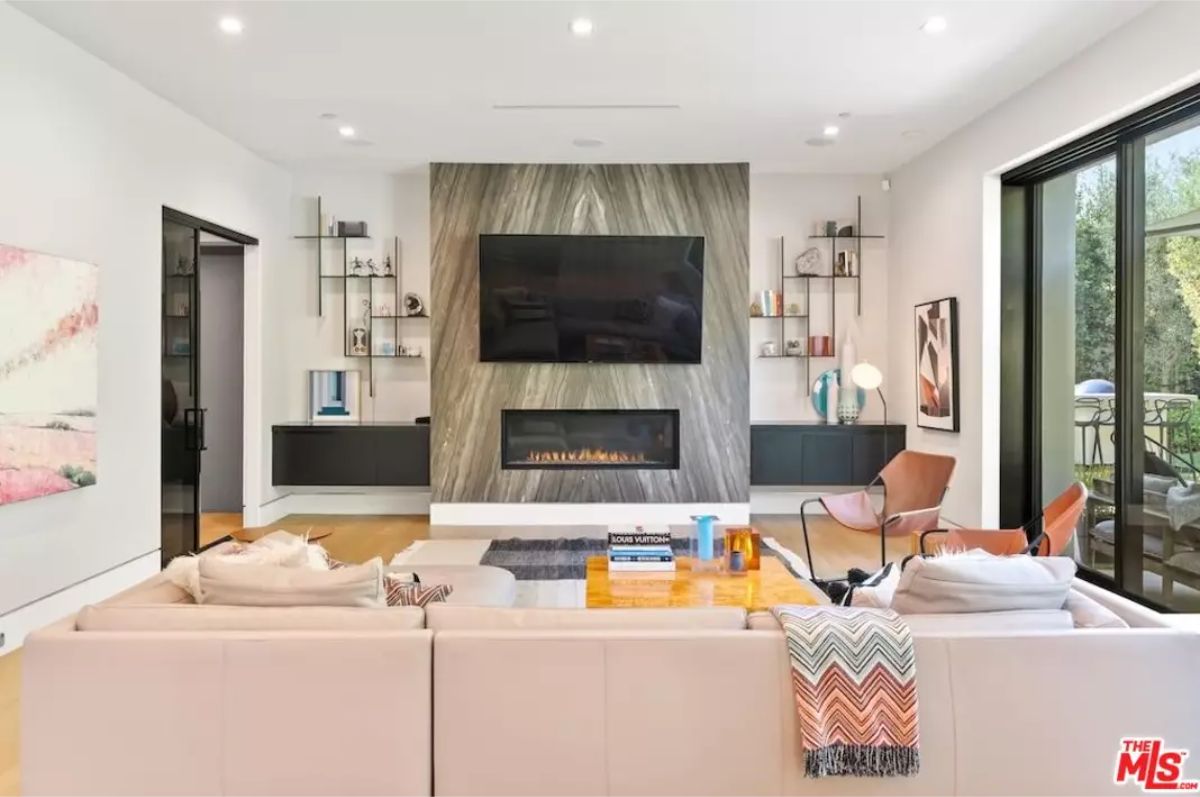 Chic entertainment area is designed with a large TV, fireplace, and modern shelves. 