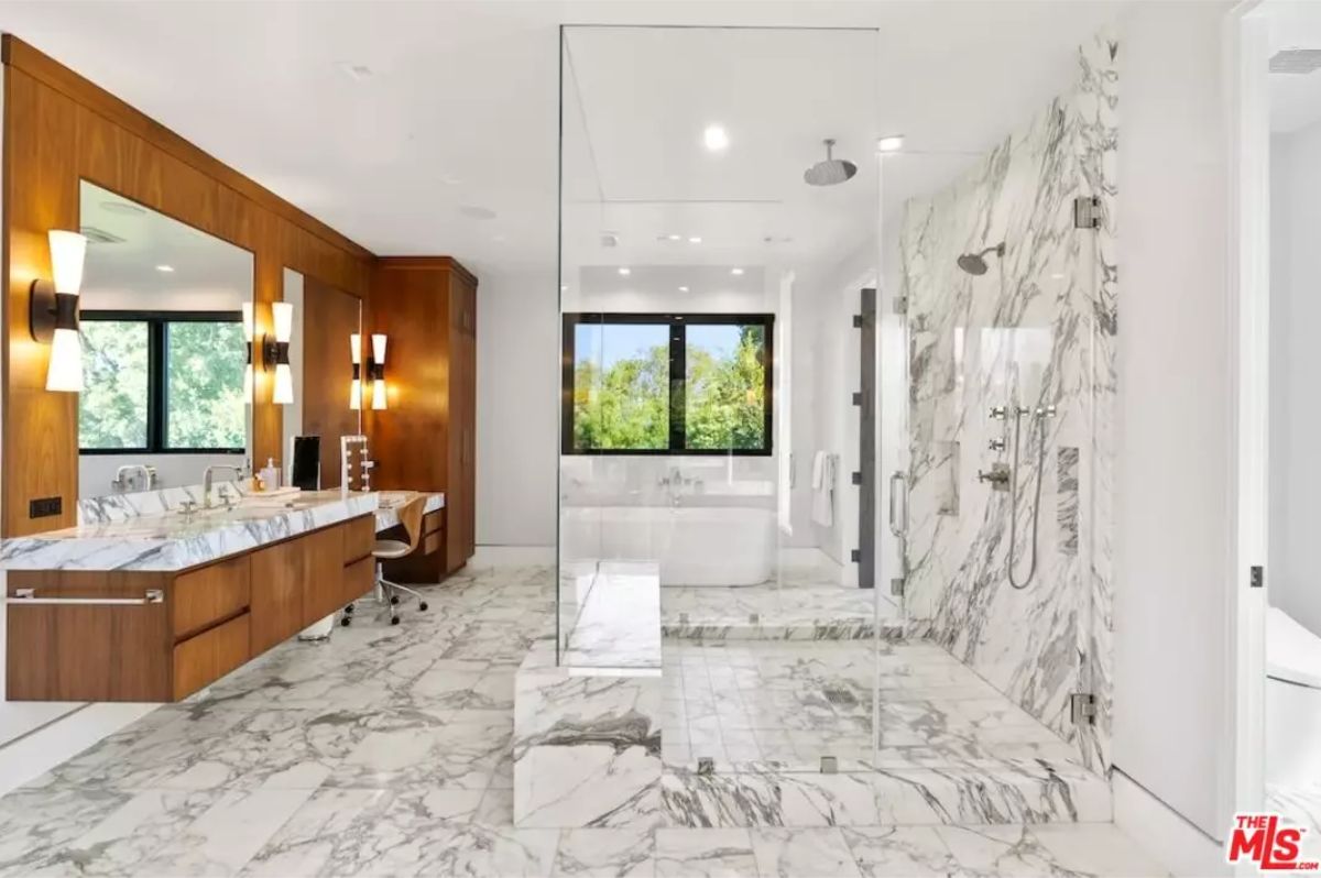 Luxurious bathroom with marble flooring, a glass-enclosed shower, and a deep bathtub. 