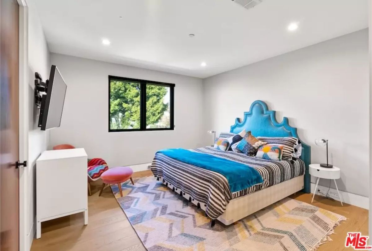 Vibrant bedroom featuring a unique blue headboard and a patterned rug. 