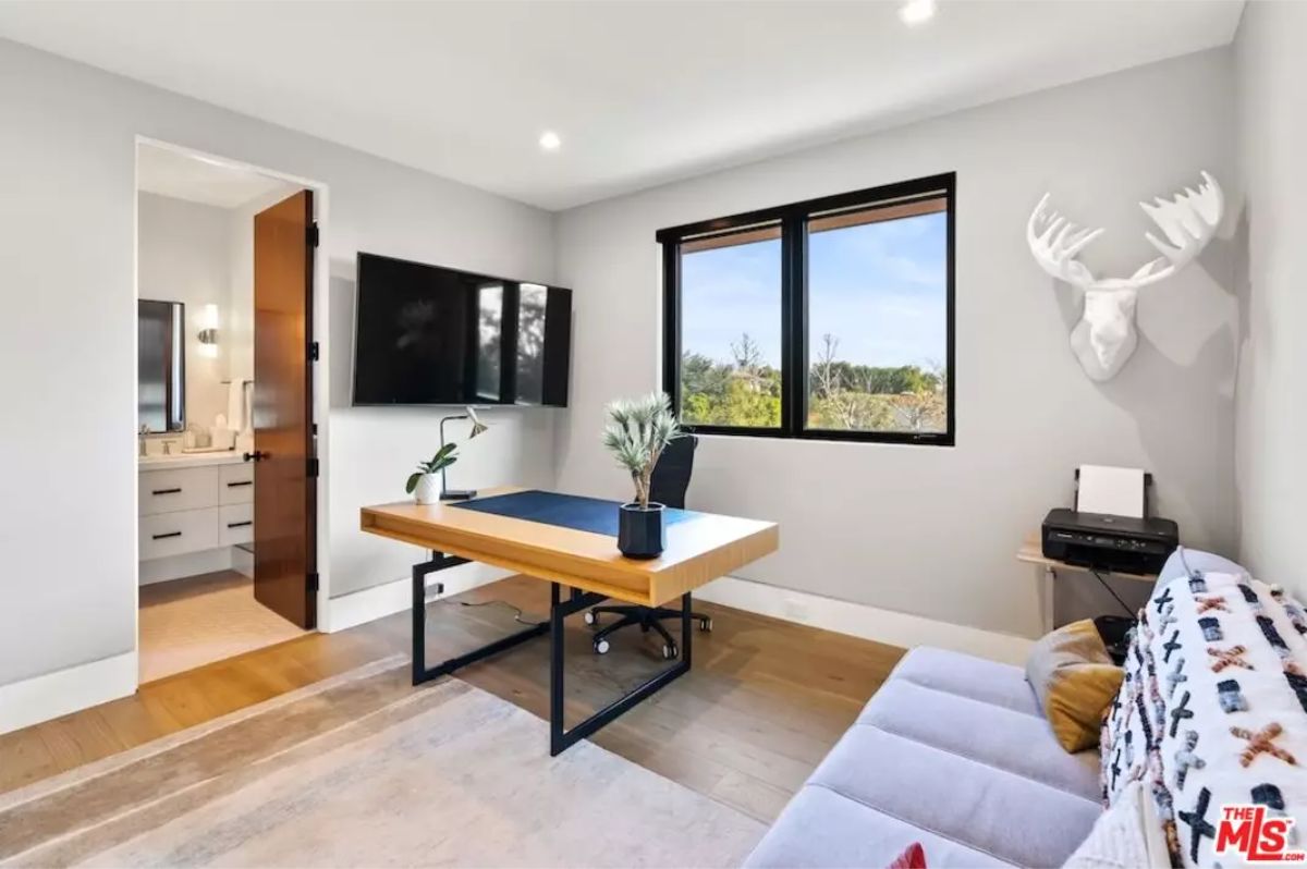 Stylish home office with a sleek wooden desk, dual monitors, and a scenic window view. 