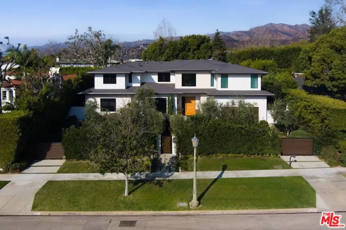 Large contemporary house features a symmetrical facade and a bright orange front door. 