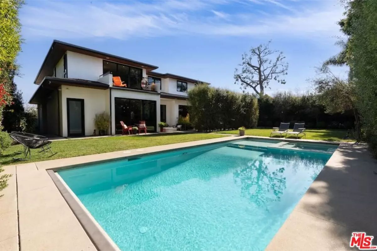 Tranquil backyard with a sparkling swimming pool surrounded by lush greenery. 