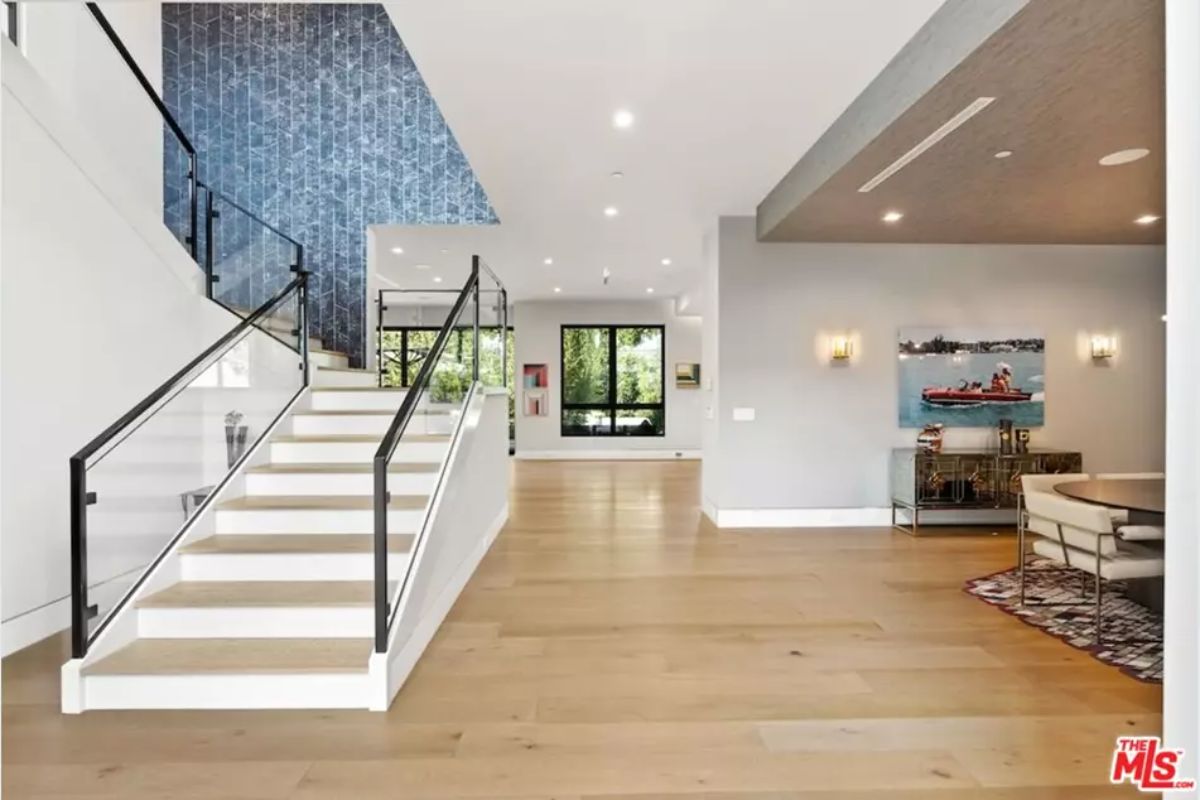 Spacious entryway is accentuated by a floating staircase with a sleek glass railing. 