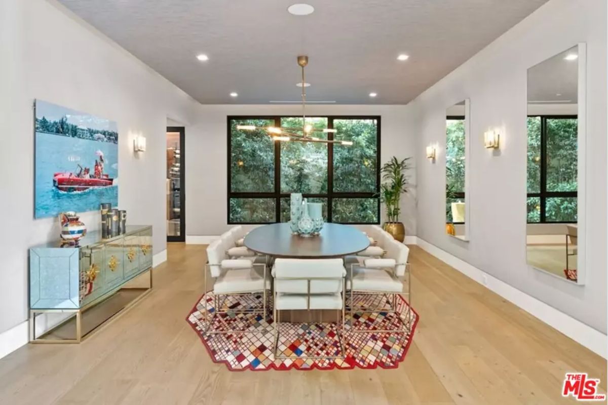 Elegant dining room features a round table, soft lighting, and floor-to-ceiling windows. 