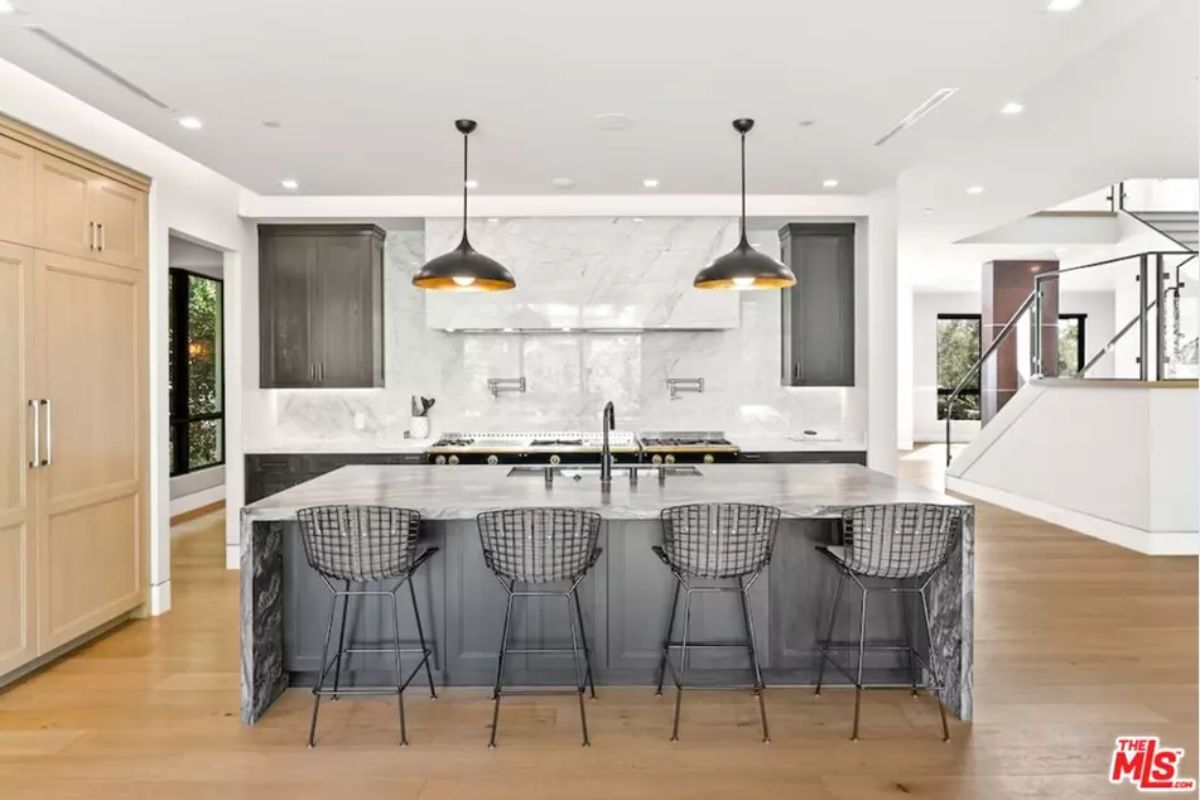 Stylish kitchen island includes bar seating, pendant lighting, and a marble backsplash. 