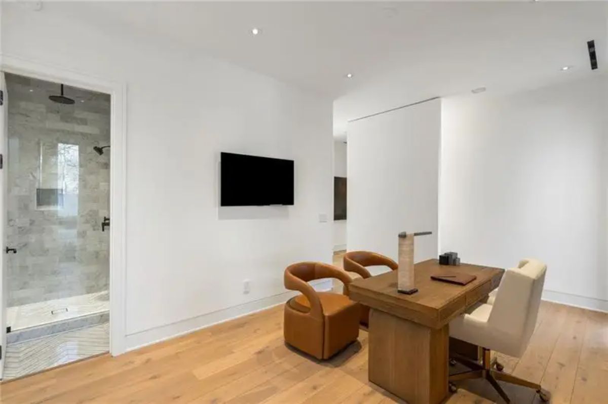 Compact office space includes a wooden desk, stylish leather chairs, and a private ensuite bathroom. 