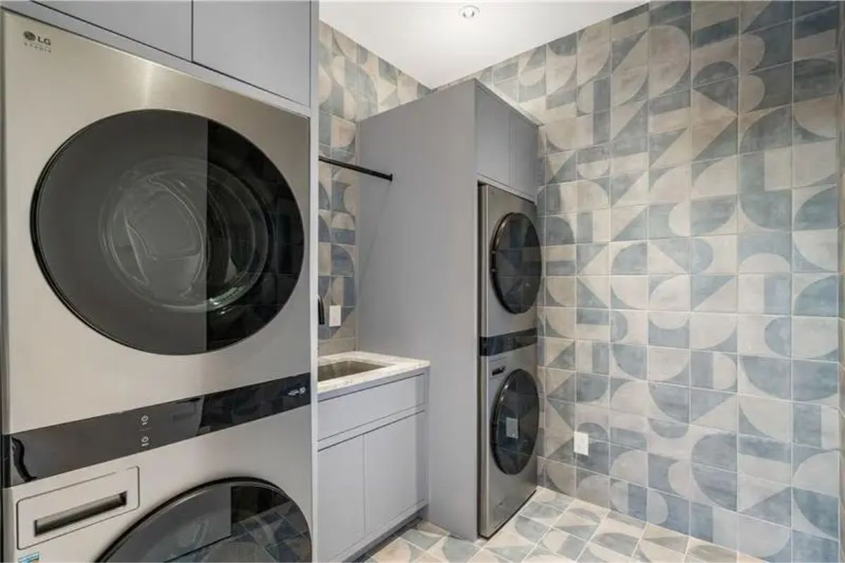 Laundry room features dual washer-dryer units, modern cabinetry, and bold geometric tile walls. 