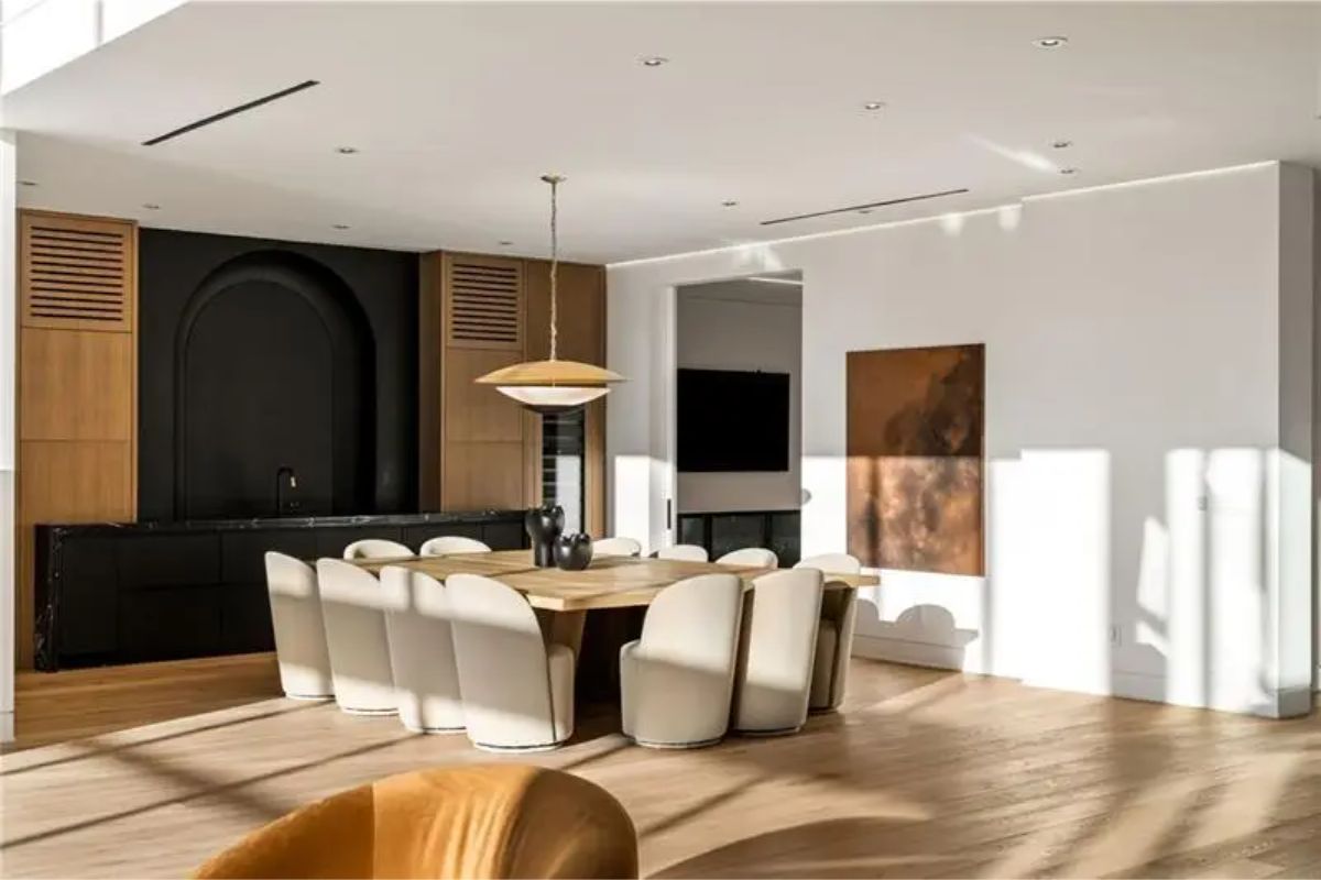 A formal dining space is styled with soft curves, warm wood, and mid-century lighting. 