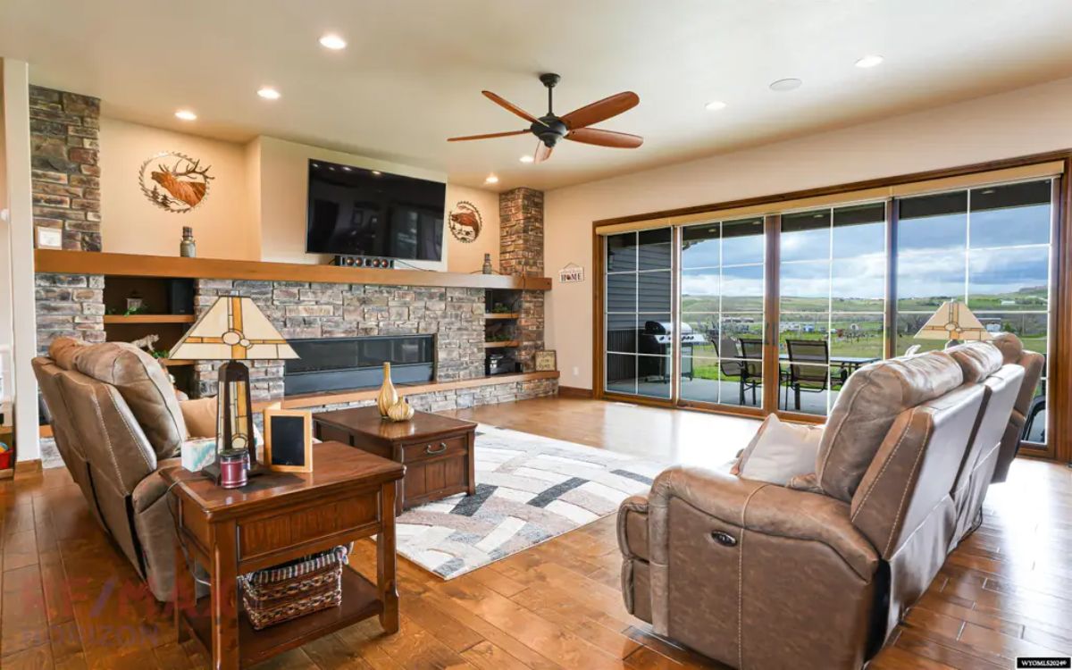 Stone fireplace extends across the wall with a mounted television above.