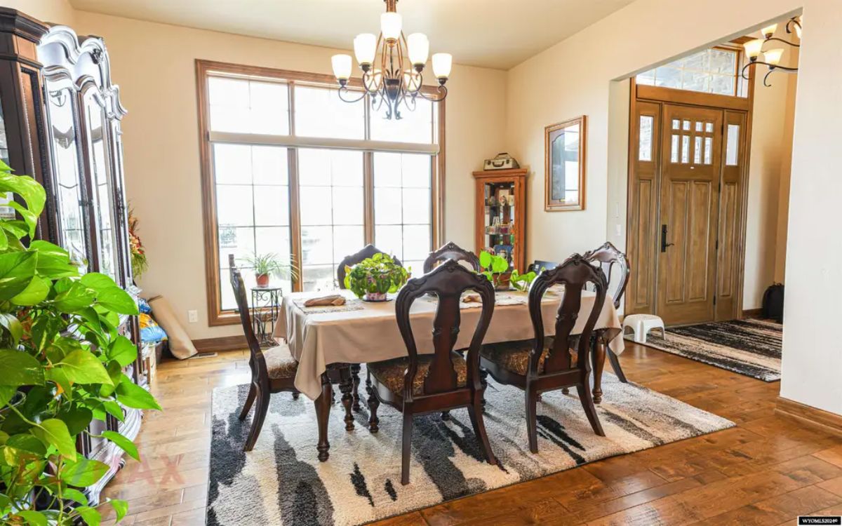 Traditional wood dining table with carved chairs is set on a patterned rug.