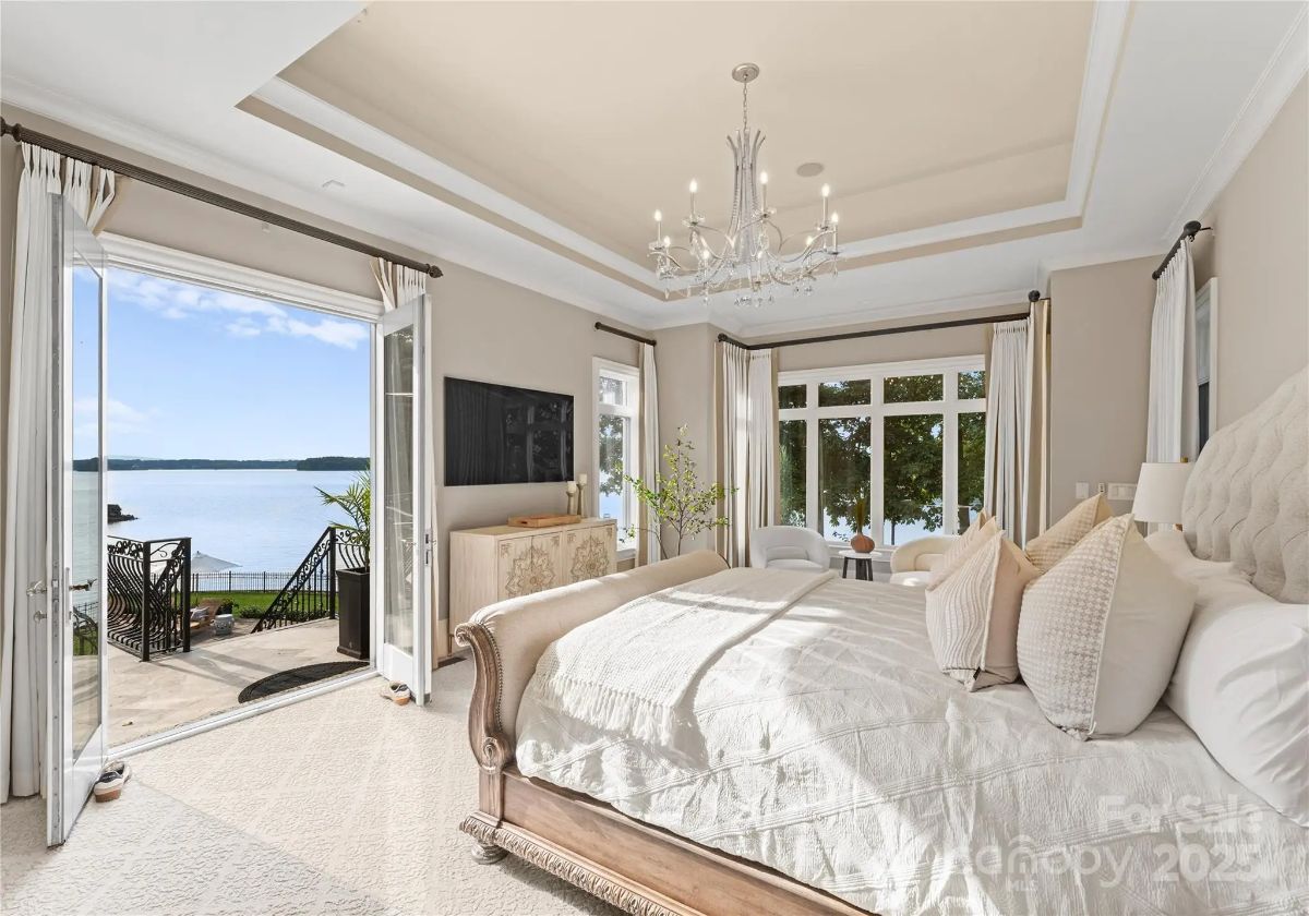 Same bedroom with French doors open to a lakefront patio and expansive water views.