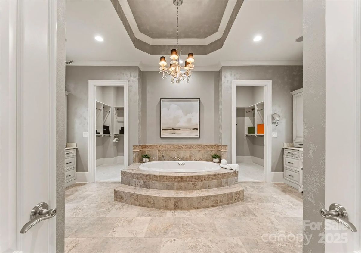 Bathroom with a large corner jetted tub, chandelier, and dual entryways to separate areas.