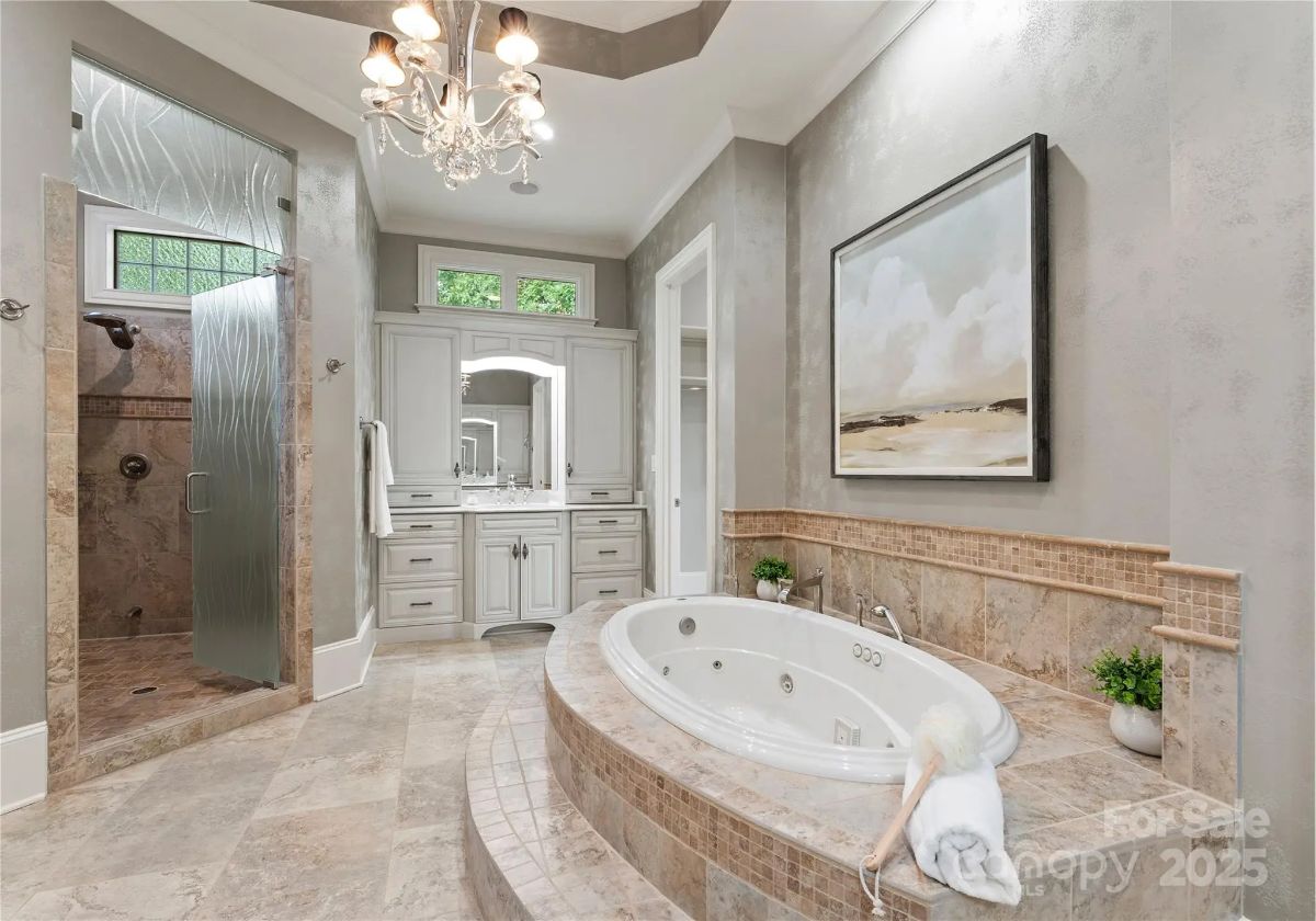 Alternate angle of the bathroom showing tub, vanity, and walk-in shower with glass partition.
