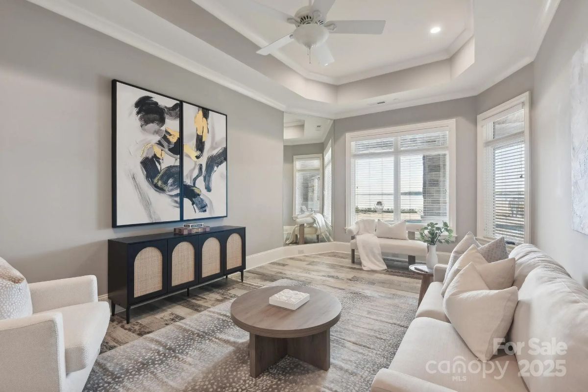 Neutral-toned living room with tray ceiling, large artwork, and natural light.