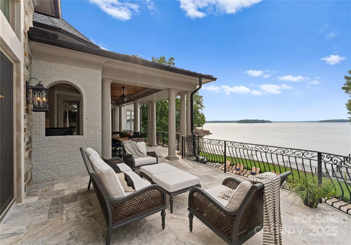 Lakefront terrace with outdoor wicker seating and wrought iron railing.