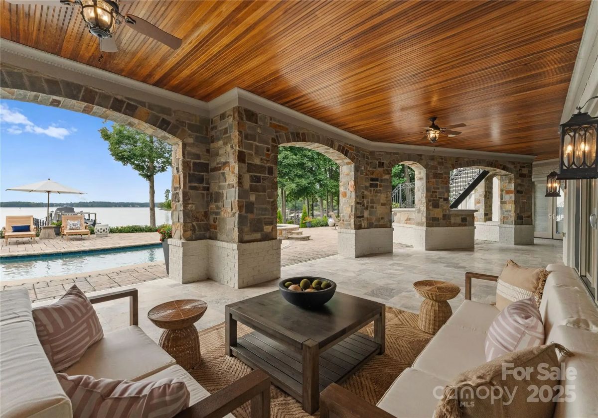 Covered patio area with cushioned seating, ceiling fans, and views of the pool and lake.