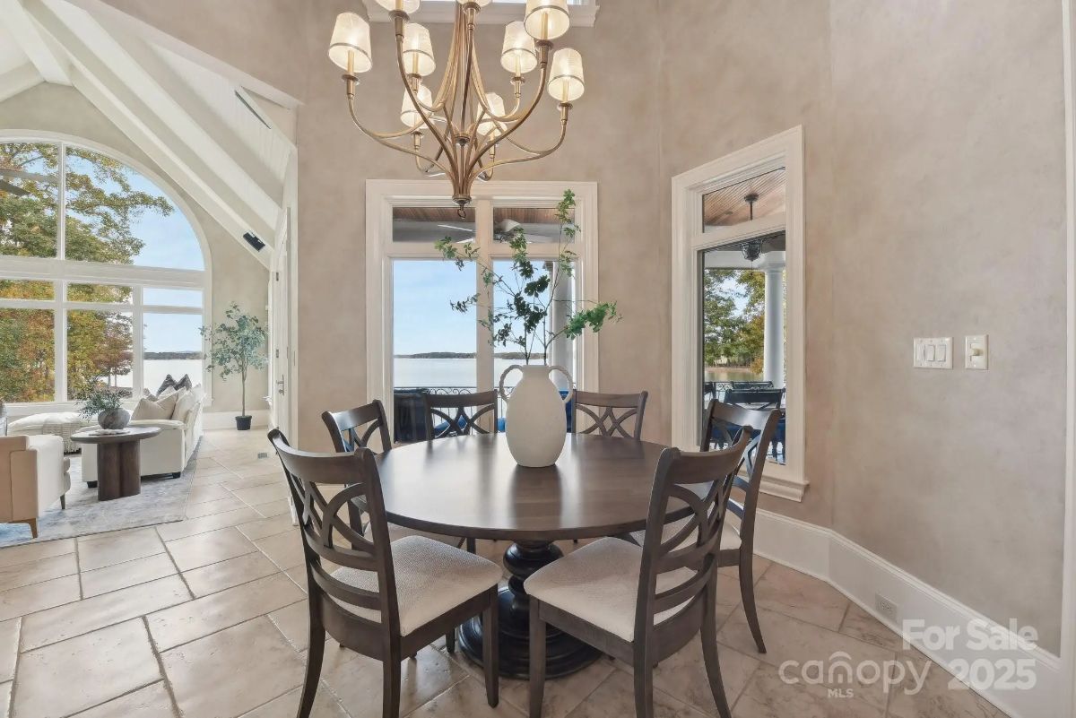 Breakfast nook with a round table, chandelier, and lake views through adjacent windows and doors.