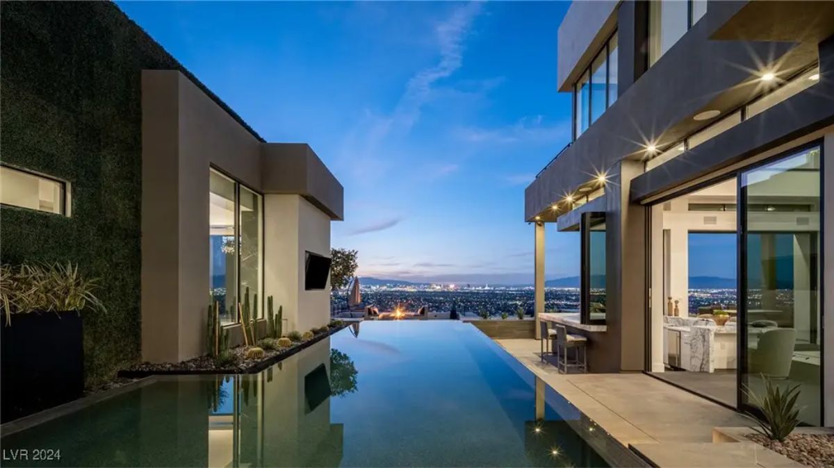 An infinity pool overlooks a city skyline at night, seamlessly blending with the modern architectural design of the residence. 