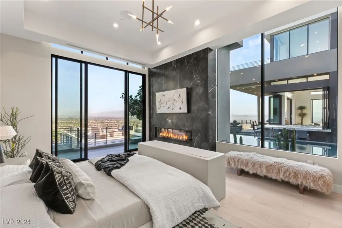 A luxurious master suite with a cozy seating area, a fireplace, and seamless access to a private terrace with panoramic views. 
