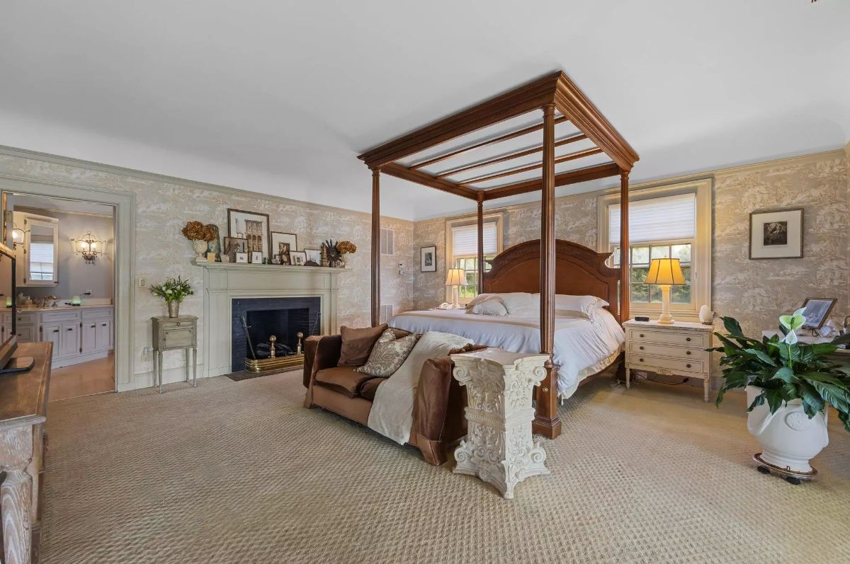 Four-poster bed sits at the center, flanked by neutral-toned nightstands and lamps.