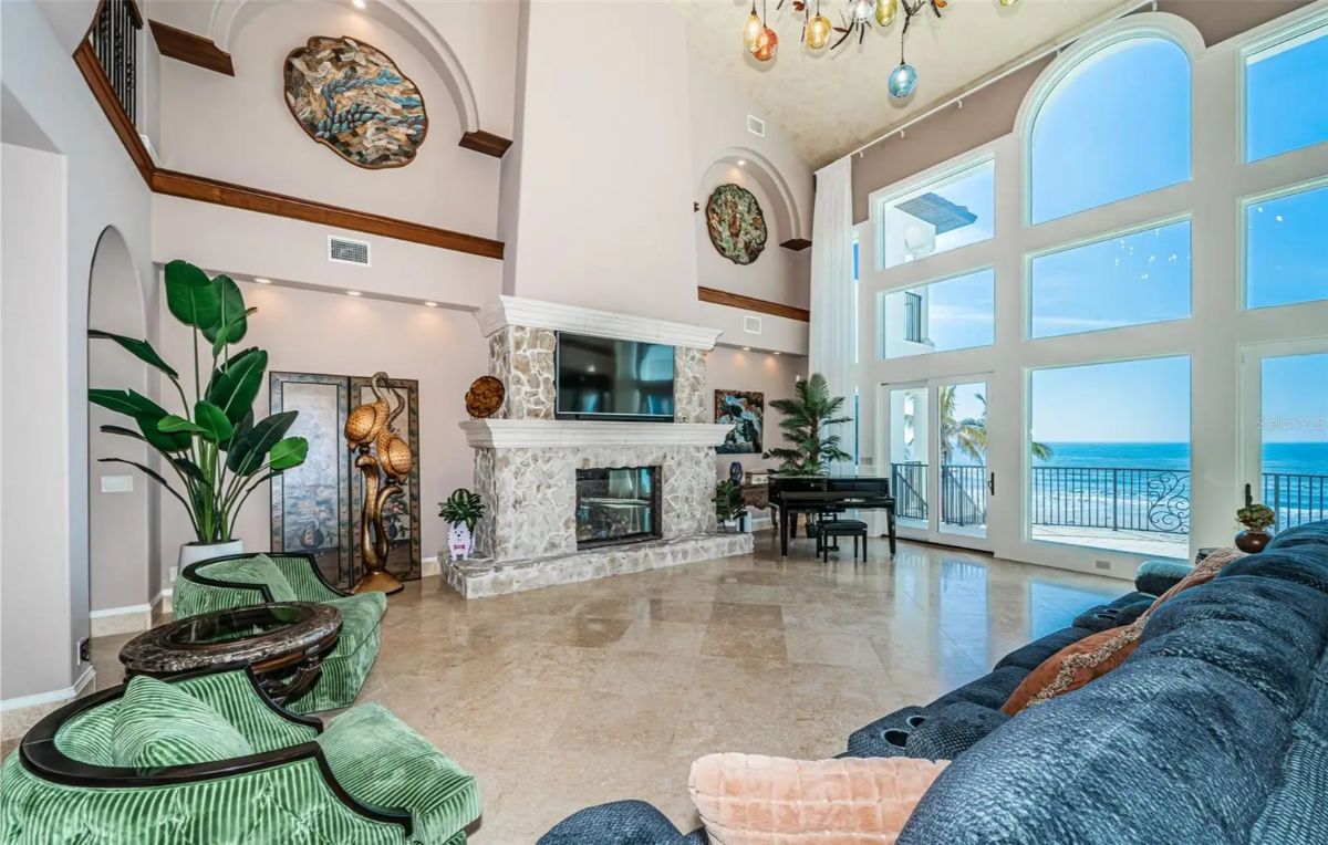 Two-story living area features tall arched windows facing the ocean.