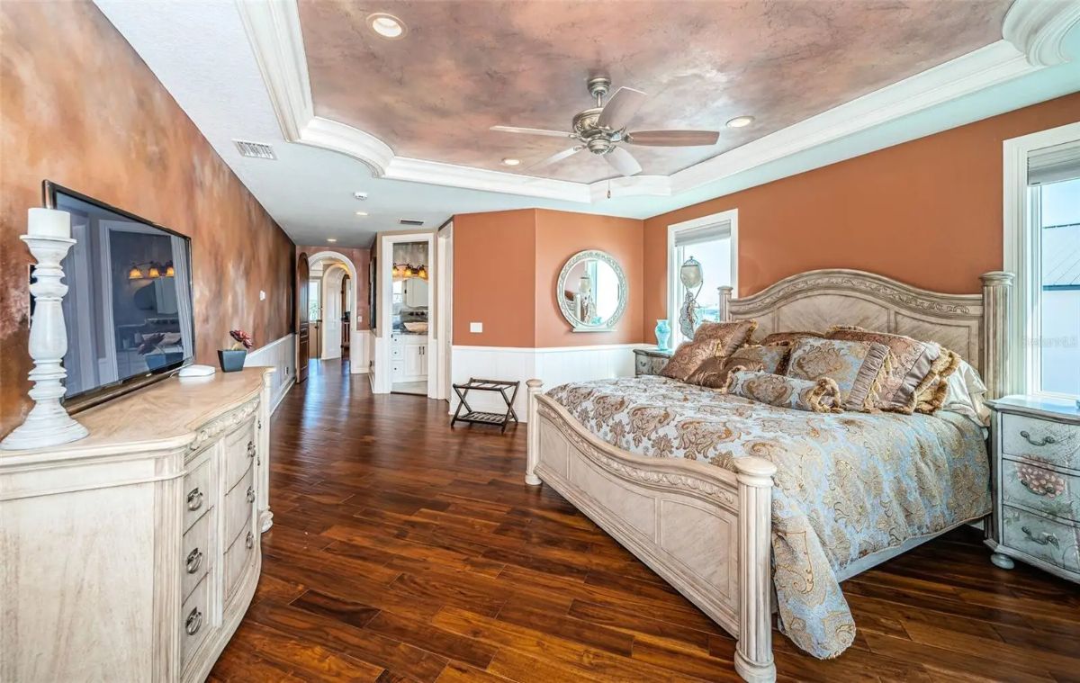 Bedroom has hardwood flooring and a tray ceiling with decorative finish.