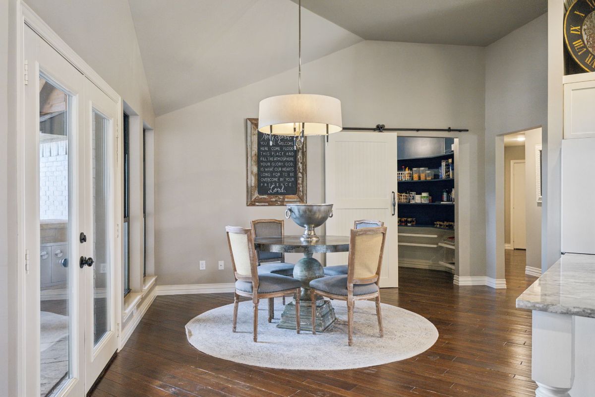 Round dining table is centered beneath a drum chandelier.