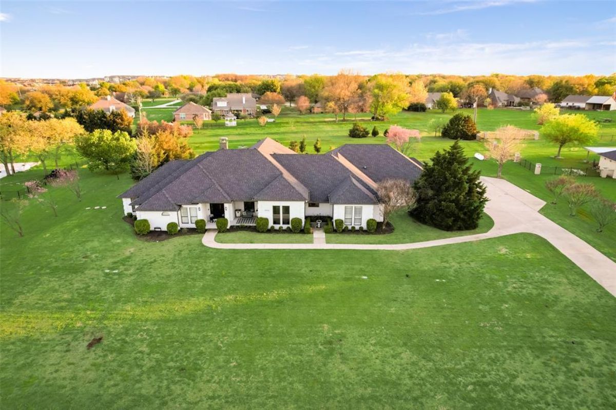 Wide lot with manicured landscaping and stone exterior. Traditional single-level ranch-style design.