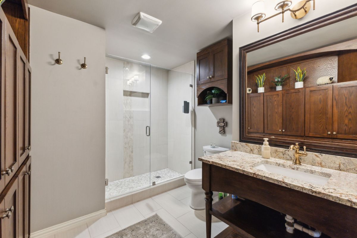 Granite countertop is paired with a dark wood vanity and matching mirror frame.