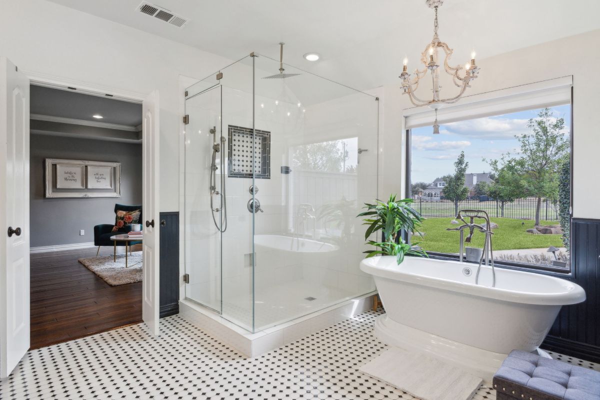 Glass shower is adjacent to a large window with outdoor views.