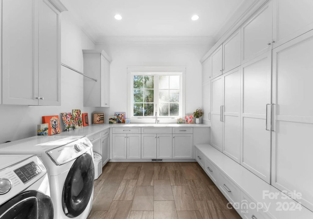 Laundry room is bright and functional with built-in cabinetry, washer and dryer, and wood flooring. 