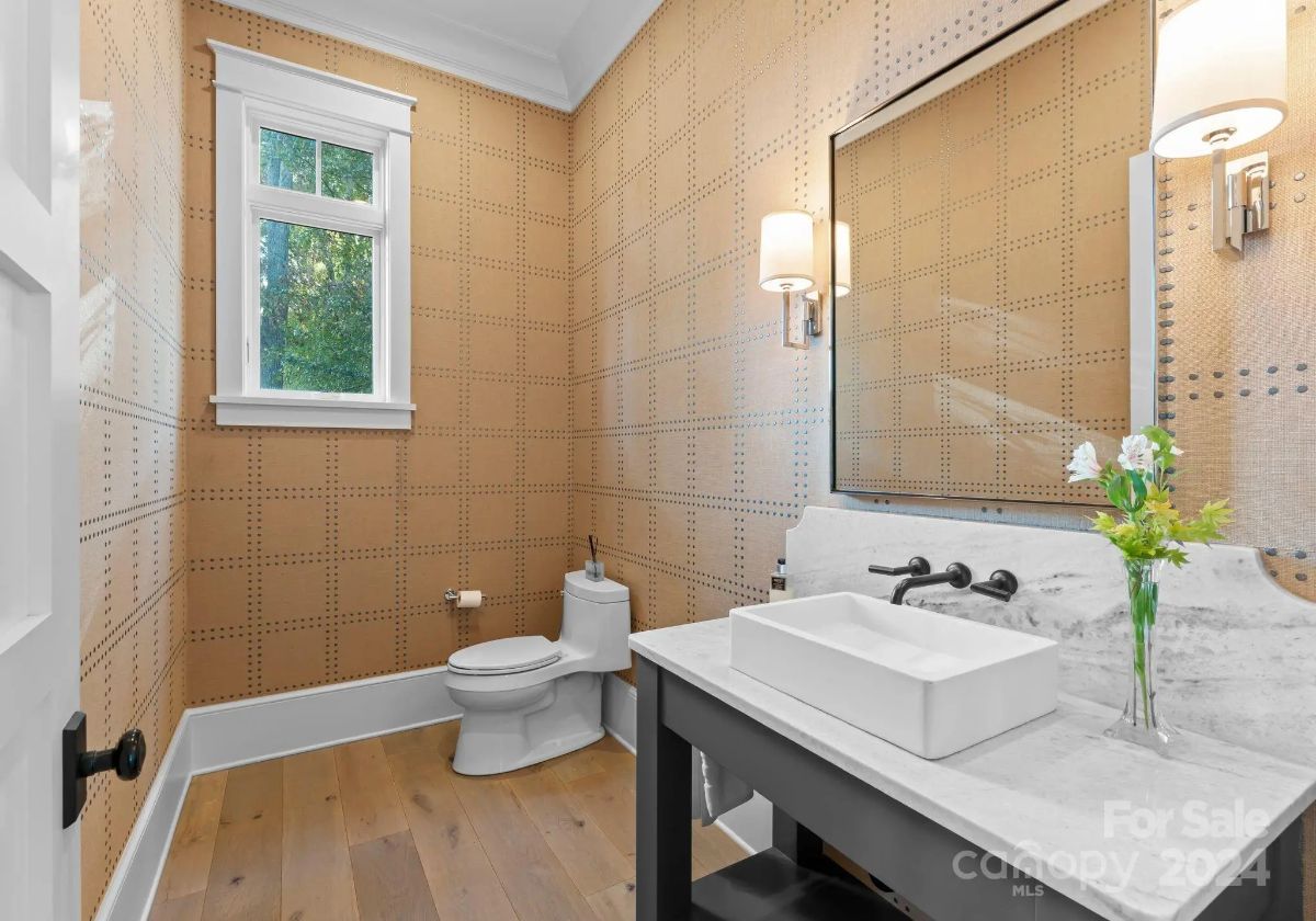 Powder room showcases modern finishes with warm-toned wallpaper and a marble vanity. 