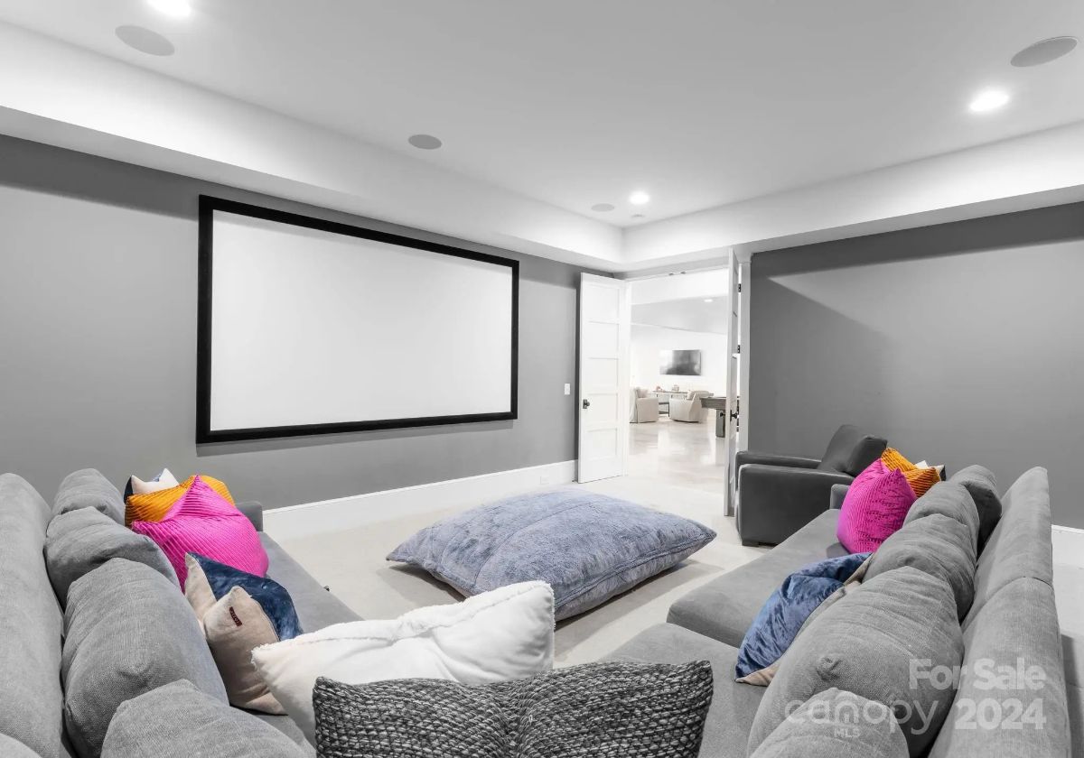 Cozy home theater features oversized sectional seating and a large projection screen. 