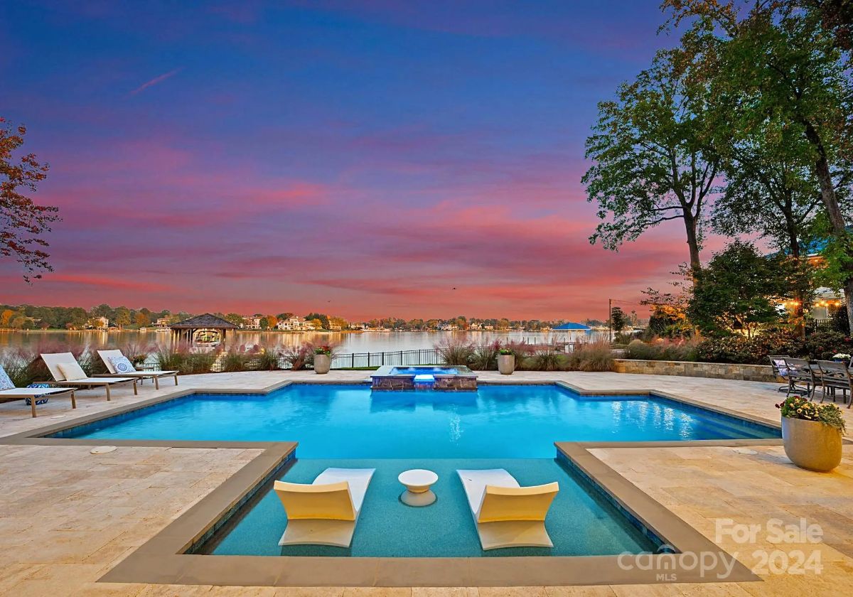 Infinity-edge pool glows at sunset, with sun loungers and lake vistas in the background. 