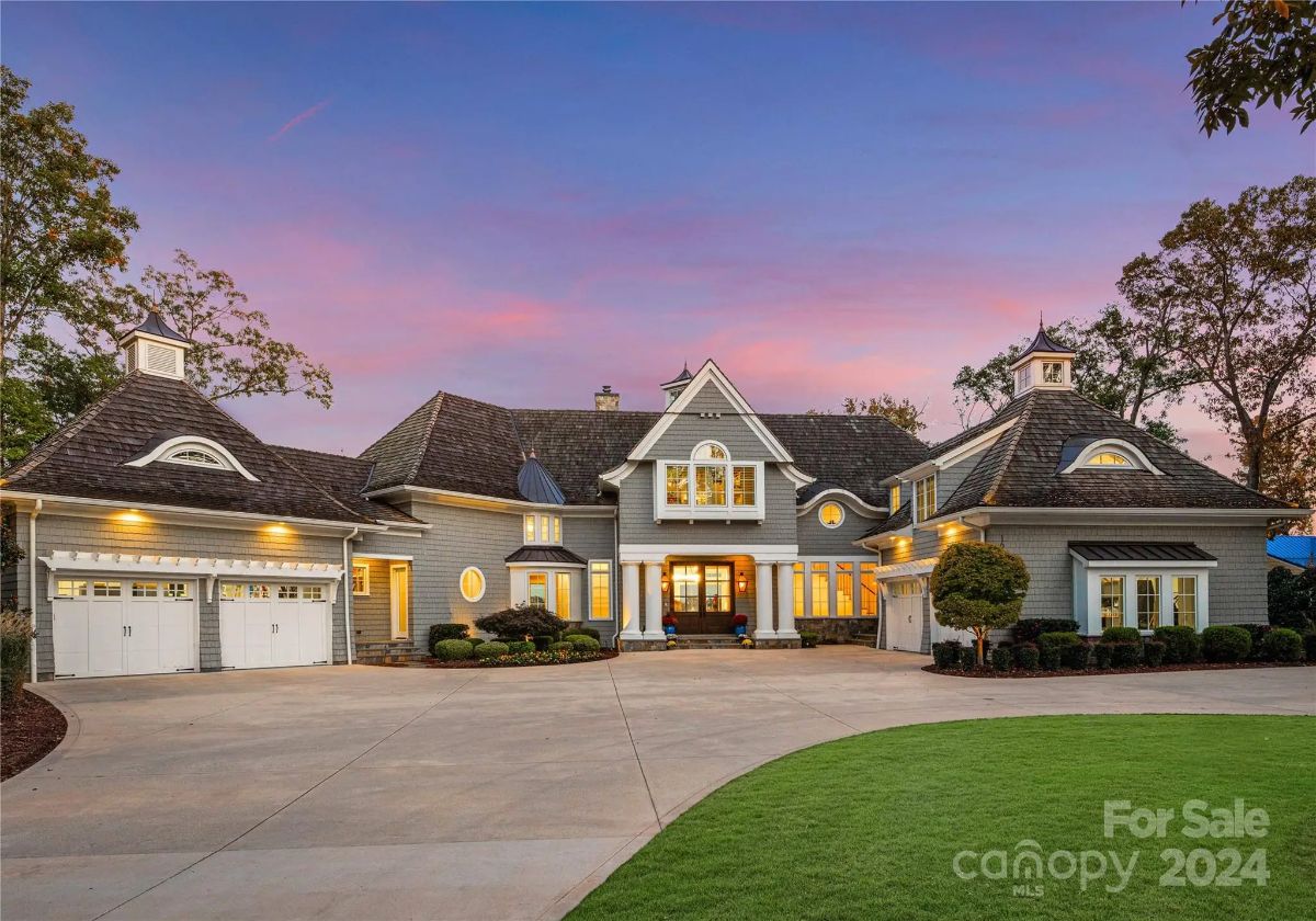 Charming gray home with dormer windows and elegant symmetry stands under a vibrant twilight sky. 