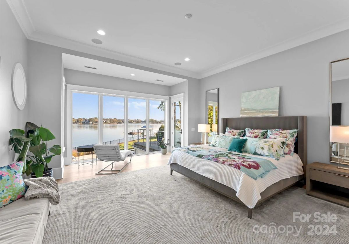 Carpeted primary bedroom opens to a lake-facing balcony through sliding glass doors.