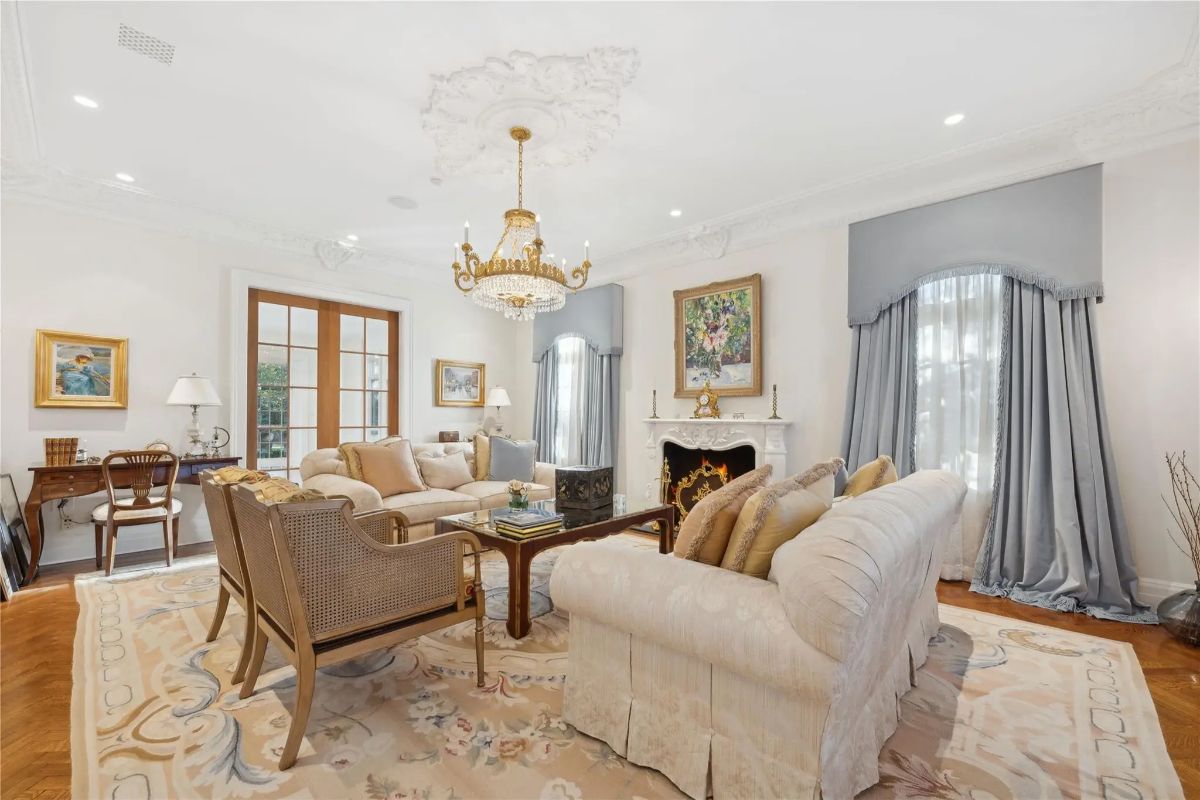 Chandelier hangs over a seating area with classic armchairs and a cream-colored sofa.