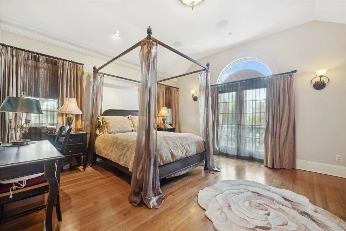 Metal-frame canopy bed is placed beneath a vaulted ceiling with recessed lighting.