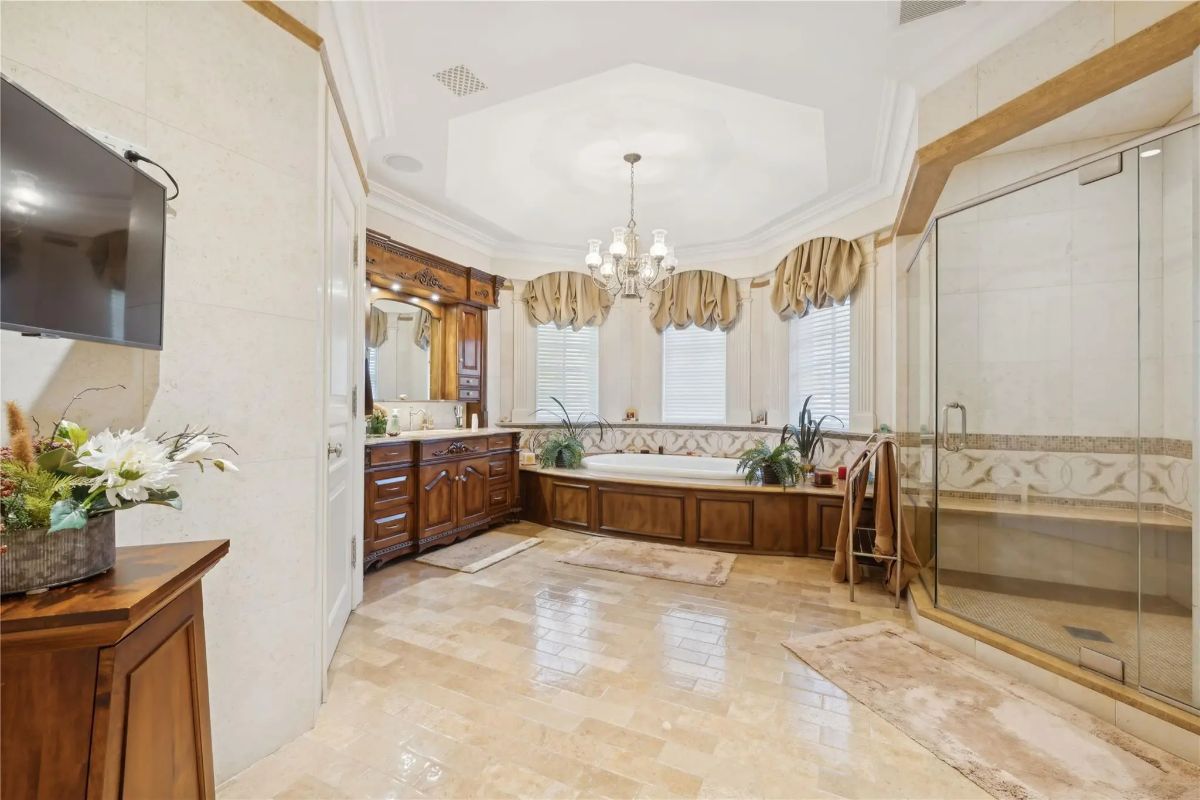 Corner bathtub is built into a wood-paneled base under three windows with valances.